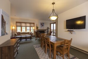 Una sala de estar acogedora con chimenea, un comedor con muebles de madera y un televisor montado.