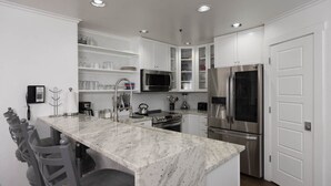 A modern kitchen with white cabinetry, a marble island, stainless steel appliances, and recessed ceiling lights. - Kendall 239 - Managed by Purgatory Resort (Durango)