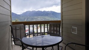 A balcony with a table and chairs, overlooking a parking area and mountains. - Cozy One Bedroom Ski Condo with Amazing Mountain Views (Durango)