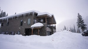 A modern building with a snow-covered roof and icicles, surrounded by a snowy landscape and trees. - Tacoma Vista 147 - Managed by Purgatory Result (Durango)