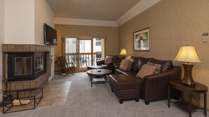 A living room with a fireplace, leather sofa, round coffee table, and two lamps. - Village Center 402 - Managed by Purgatory Resort (Durango)