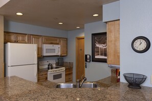 Compact kitchen with a functional layout, featuring a refrigerator, microwave, and stove, along with ample workspace and a convenient sink.