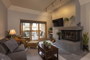 A living room with a fireplace, a sofa, a coffee table, and a TV mounted on the wall.