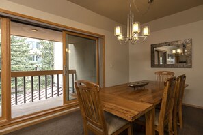Enjoy meals in this dining area with a table, chairs, and a mirror, surrounded by a balcony with a view of the building and trees.