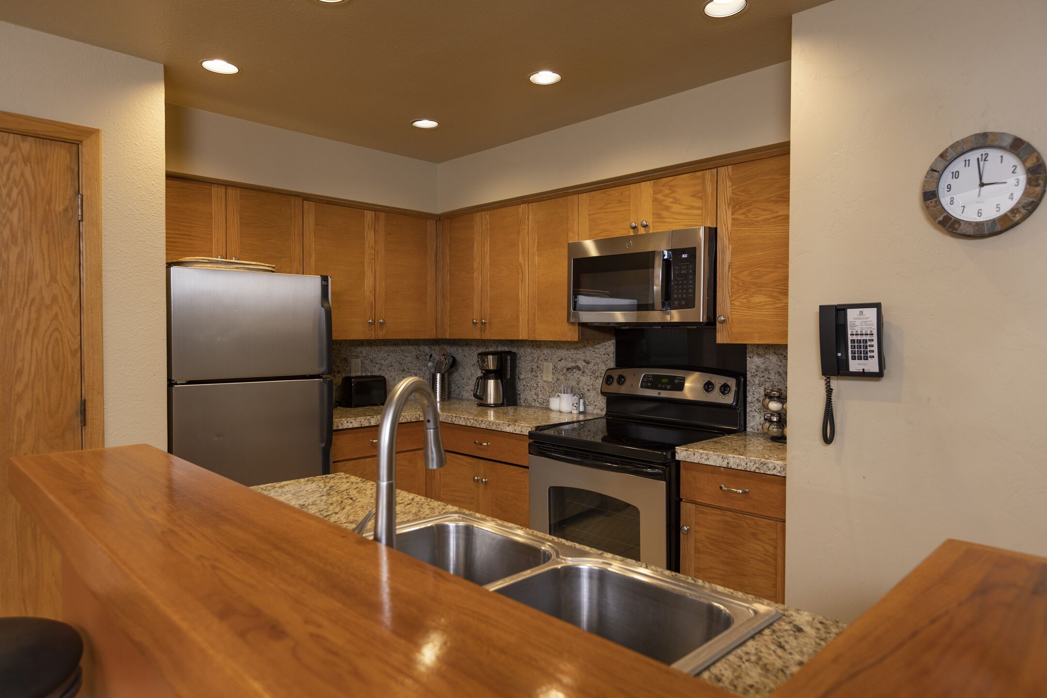 A kitchen with wooden cabinets, stainless steel appliances, granite countertops, and a built-in oven.