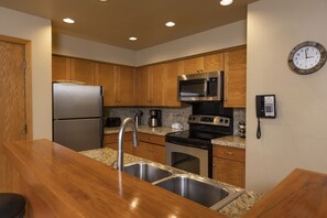 Features a kitchen with stainless steel appliances, wooden cabinetry, and granite countertops.
