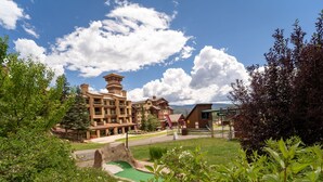 A resort with multiple buildings, a green lawn, and a mountainous backdrop. - Village Center 512 - Managed by Purgatory Resort (Durango)