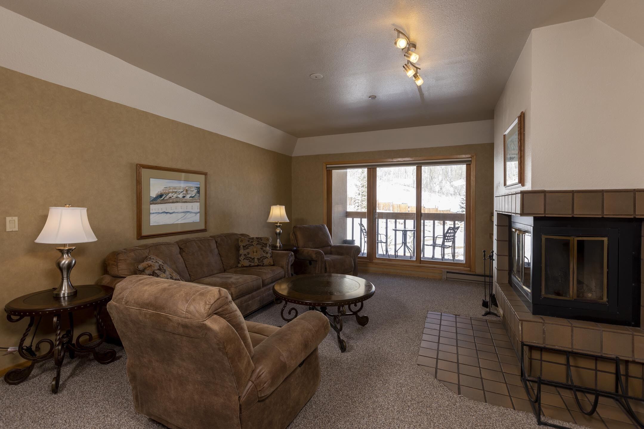 A living room with a fireplace, a sofa, a coffee table, and a lamp.