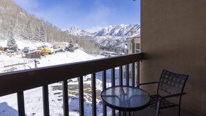 A balcony with a view of a snowy mountain landscape, a table, and chairs. - Village Center 512 - Managed by Purgatory Resort (Durango)