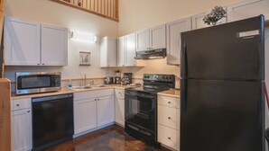 A kitchen with white cabinets, a black refrigerator, a microwave, a dishwasher, and a stove. - Cabin C at Safe Harbor Brady Mountain on Lake Ouachita! (Royal)