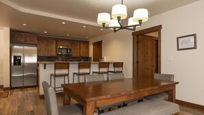 Una cocina moderna con armarios de madera, un refrigerador de acero inoxidable, un microondas y un comedor con una mesa y sillas de madera.
