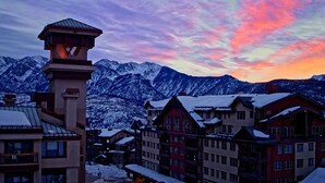 A snow-covered mountain town at dusk with buildings and a prominent tower.