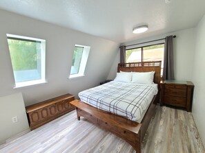 Relax in a serene bedroom with a comfortable bed, nightstand, and sloped ceiling.