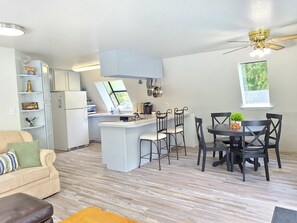 Compact apartment with a central kitchen area, featuring a kitchen island and bar stools, and a cozy living space with a sofa and coffee table.