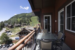 Enjoy breathtaking views of the surrounding mountains from this balcony, featuring a table and chairs.
