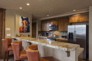 Enjoy cooking in this well-equipped kitchen with a central island, wooden cabinets, and a granite countertop.