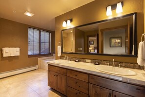Une salle de bain avec deux lavabos, un grand miroir et des meubles en bois.