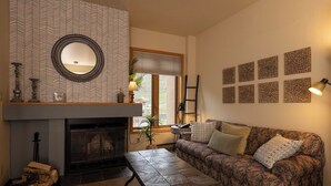 A cozy living room with a fireplace, patterned wallpaper, a sofa, and decorative wall art. - Cozy Studio for 2 at Purgatory Village - Kendall 335, Durango, CO with Plaza View. (Durango)