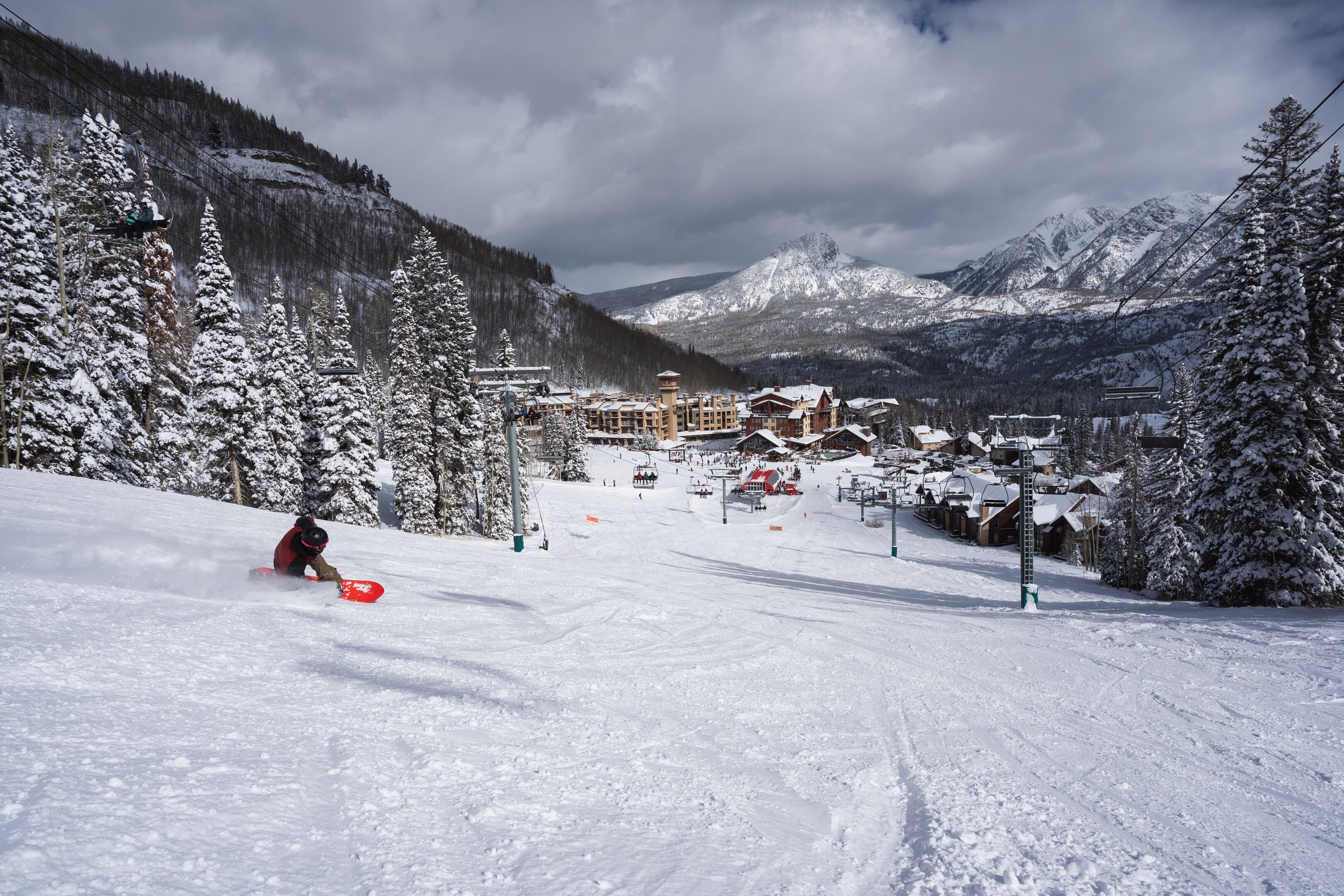 Une piste de ski enneigée, avec un chalet visible au loin.