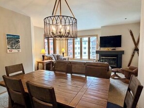 A dining area with a wooden table and chairs, a large chandelier, and a sofa set. - Kendall 236 - Managed by Purgatory Resort (Durango)