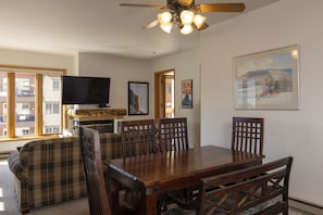 Un comedor con una mesa y sillas de madera, un televisor y una chimenea.