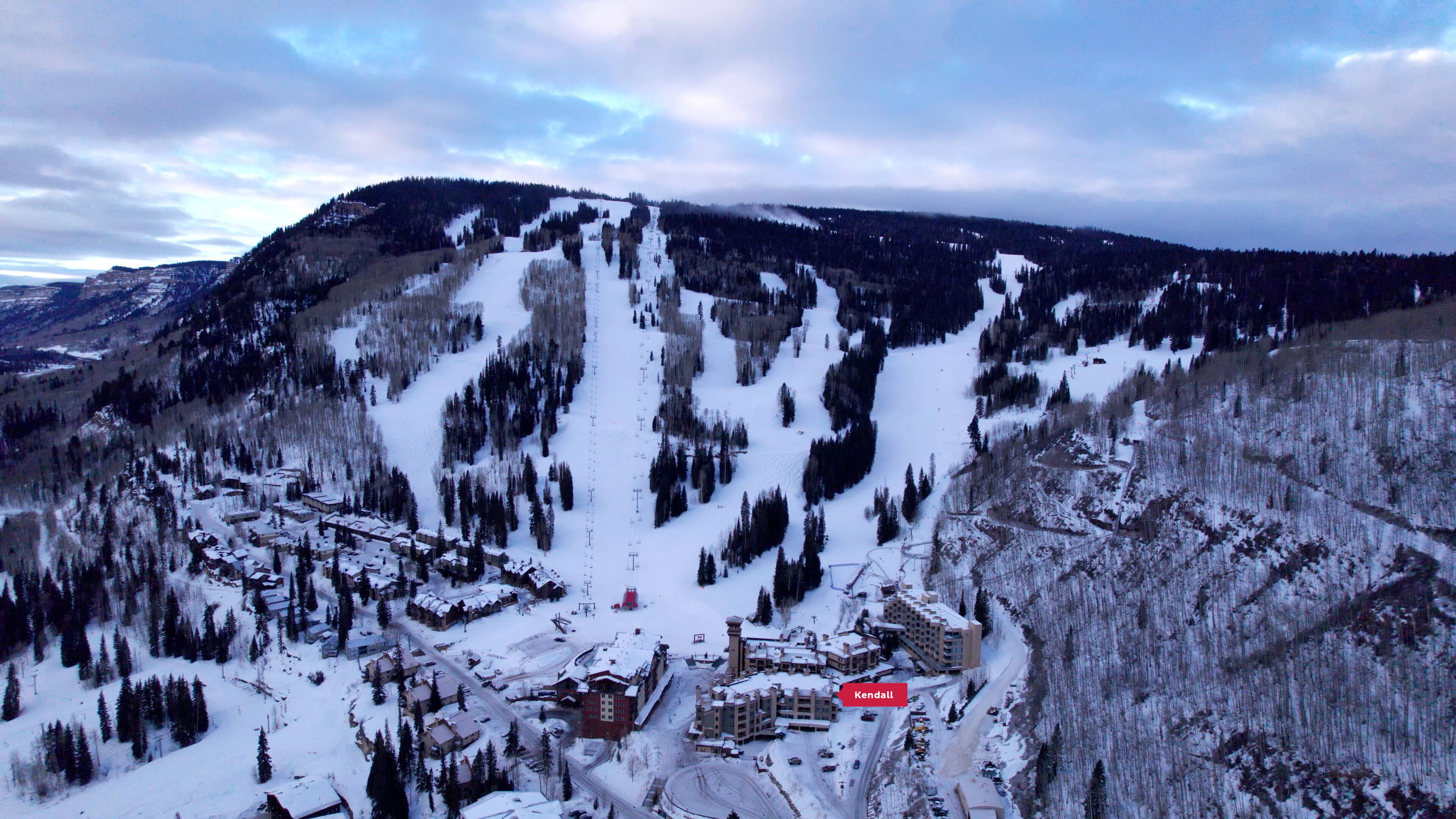 A snow-covered mountain town with a ski resort, including buildings and ski lifts.