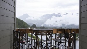 A balcony with a table and chairs overlooking a mountainous landscape with a lake and a parking area. - Kendall 540 - Managed by Purgatory Resort (Durango)