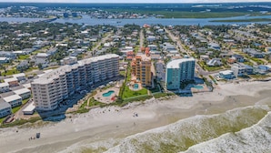 A coastal resort with multiple high-rise buildings, a beachfront, and a marina. - Gorgeous Oceanfront View! Walking distance to dining & shopping! (New Smyrna Beach)