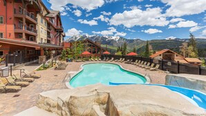 A pool area with lounge chairs, a stone waterfall feature, and a mountain backdrop. - Purgatory Lodge 101 -  Managed by Purgatory Resort (Durango)