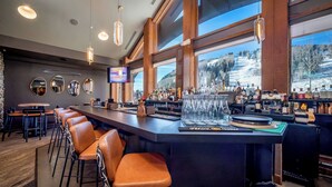 A bar area with a long counter, stools, and a view of a snowy landscape through large windows. - Purgatory Lodge 101 -  Managed by Purgatory Resort (Durango)