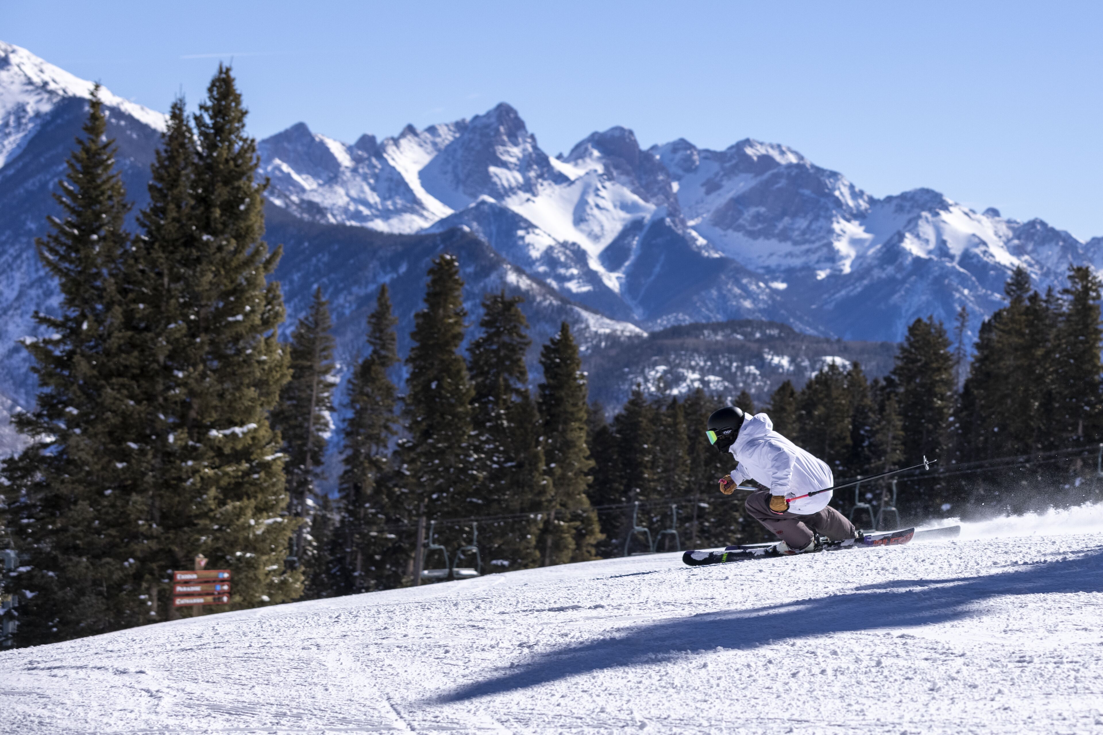 A skier on a snowy slope with a mountainous backdrop.