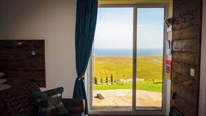 Een kamer met een grote schuifglazen deur die uitkomt op een gazon met uitzicht op de zee.