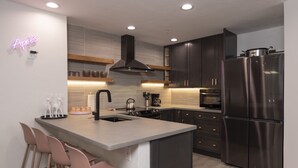 Una cocina moderna con una isla central, electrodomésticos de acero inoxidable y un letrero de neón.