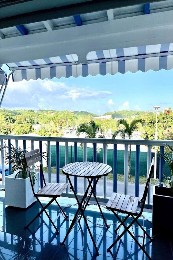 A covered outdoor area with a pool, two wooden chairs, and a table.