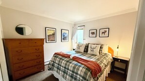 A bedroom with a bed, dresser, and wall art.