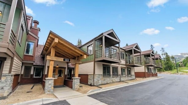 A multi-story building with a stone facade, a wooden entrance, and a balcony.