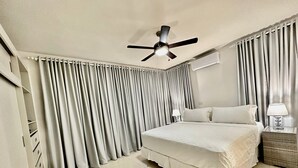 A bedroom with a bed, a ceiling fan, a nightstand with a lamp, and a window with curtains. - CASA COCO-MODERNO Superior 4 Master @ Casa Linda (Sosua)