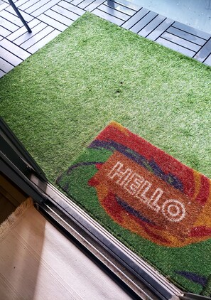 Welcome to a stylish entrance with a personalized doormat and lush artificial grass flooring.