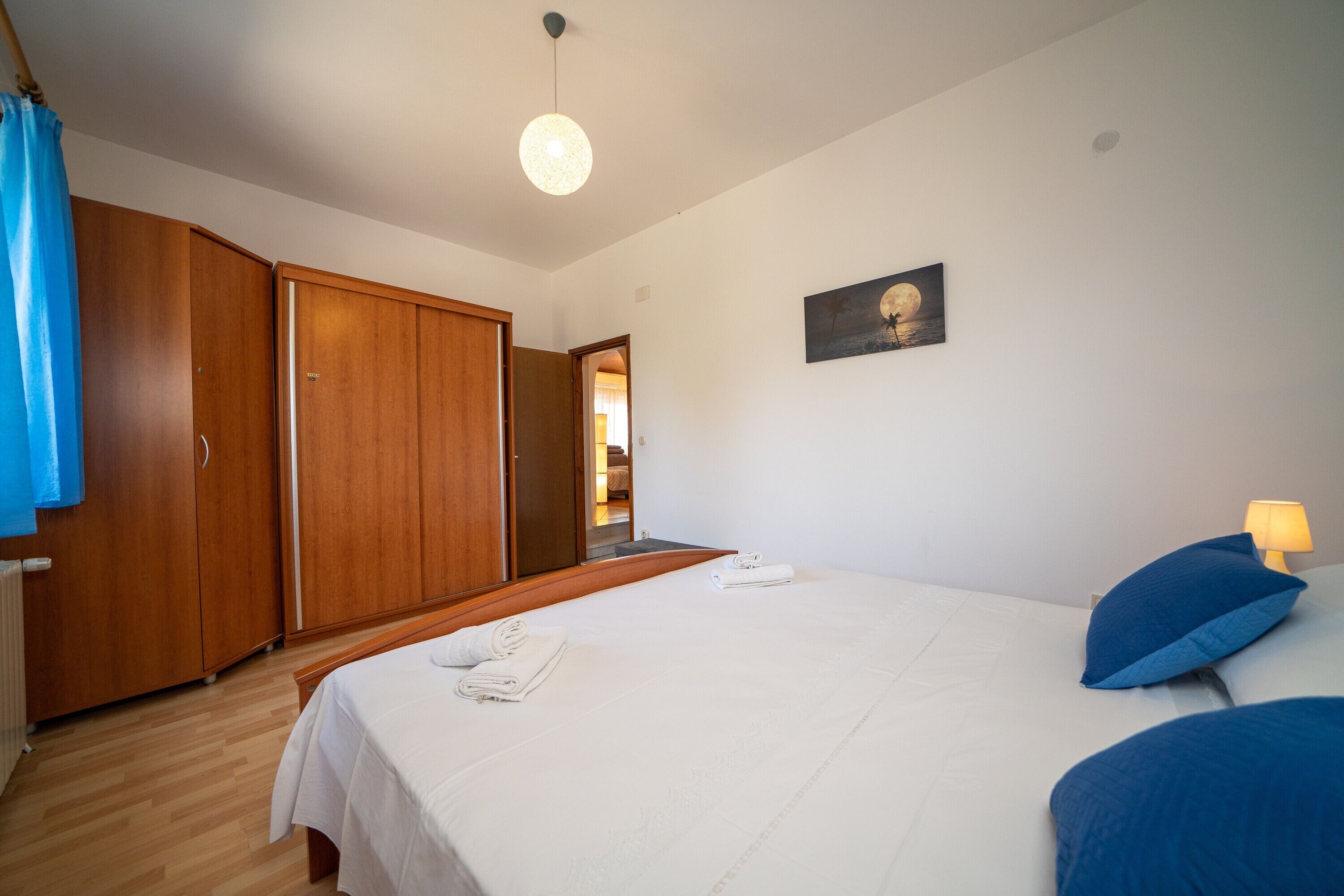 Une chambre à coucher comprenant un lit, une armoire, une porte donnant sur une autre pièce et un tableau accroché au mur.