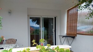 A balcony with a sliding glass door, a small table, and a chair. - Apartments Dijana - Studio Apartment with Terrace (Viganj)