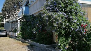A building with a balcony, a gravel driveway, and a tree with purple flowers. - Apartments Dijana - Studio Apartment with Terrace (Viganj)
