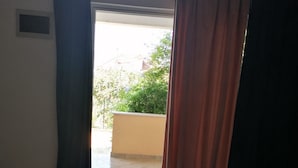 A room with a bed, a window with curtains, and a view of a balcony and greenery outside. - Apartments Dijana - Superior Studio Apartment with Terrace (Viganj)