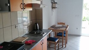 Una cuina amb armaris taronja, una cuina i una zona de menjador amb una taula i cadires.