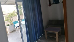 Una habitació amb una porta corredissa de vidre que dona a una zona exterior, una taula de fusta petita i un sofà.