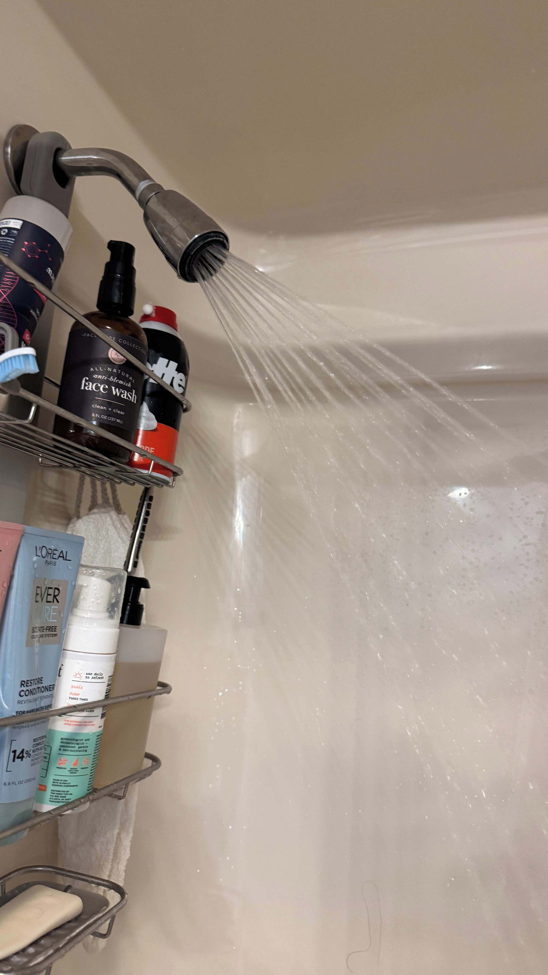 Un baño con ducha, un estante con artículos de aseo y una bañera.