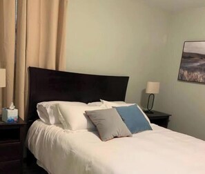Una camera d'albergo con un letto, un comodino, una lampada e un quadro appeso al muro.