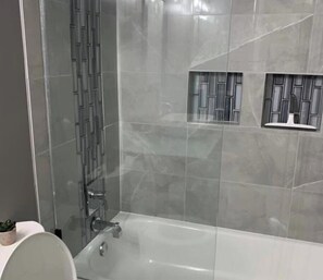 Un bagno moderno con doccia vetrata, vasca e servizi igienici.
