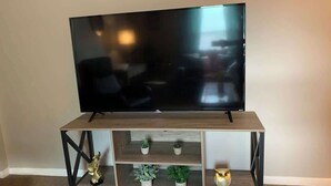 Un téléviseur posé sur un meuble en bois, avec des étagères où sont disposés des objets décoratifs.