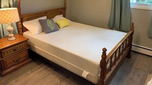 Un lit bien fait, avec une tête de lit en bois, une lampe de chevet et un tableau accroché au mur.