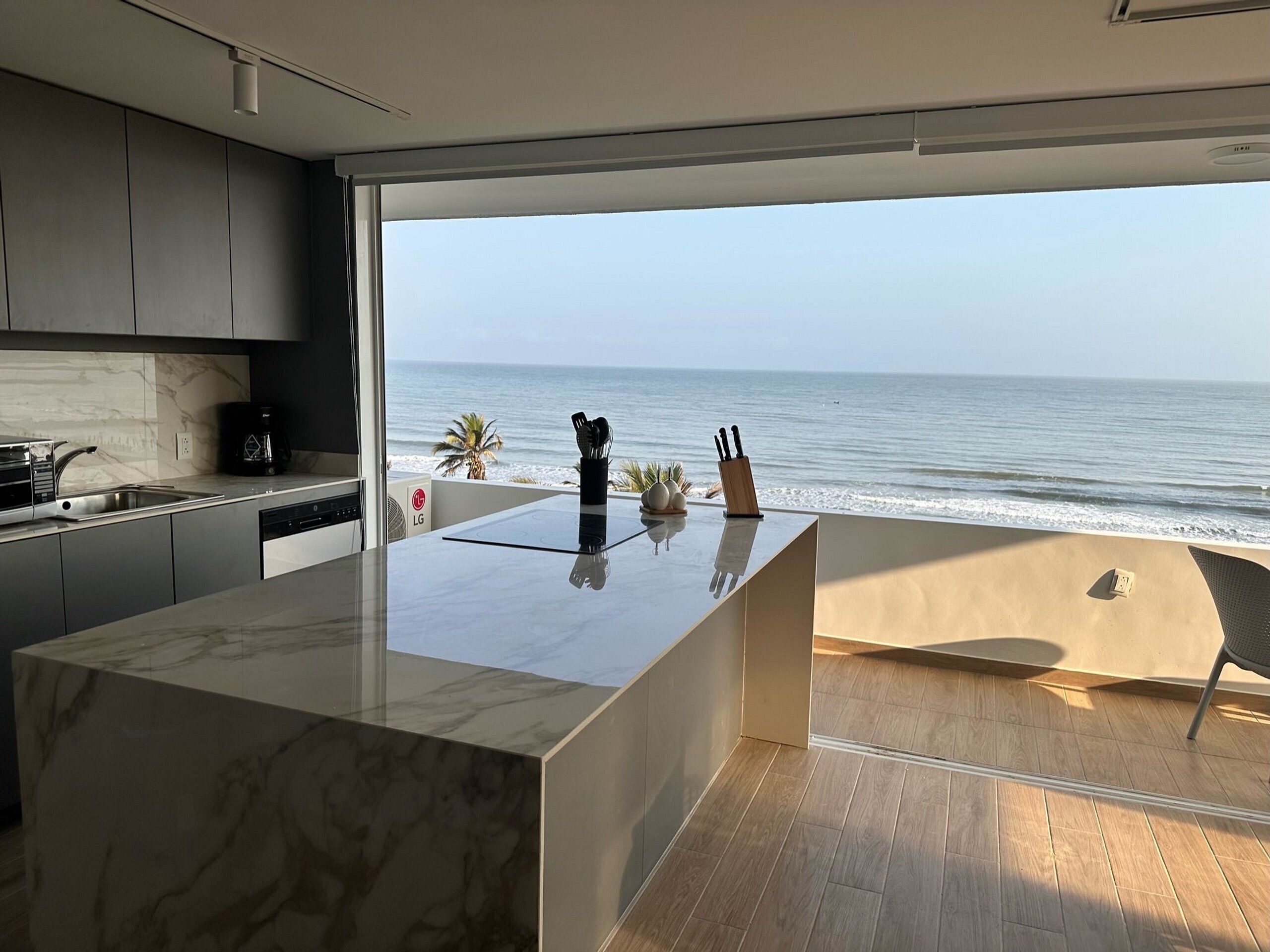 Cozinha moderna com uma ilha grande, máquina de lavar louça e vista para o oceano.